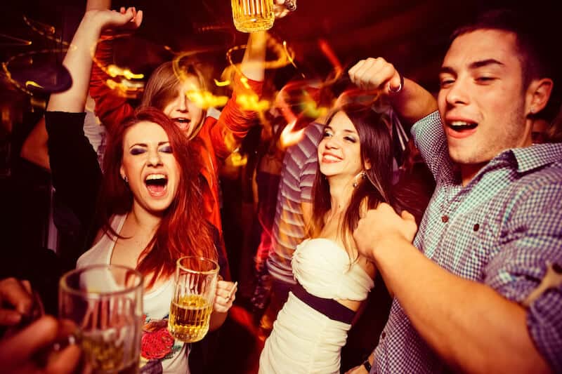 young adults drinking and dancing in a bar